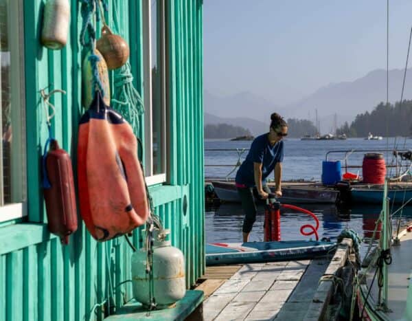 Pagaie pour optimist devant un cabanon marin au bord de l'eau.
