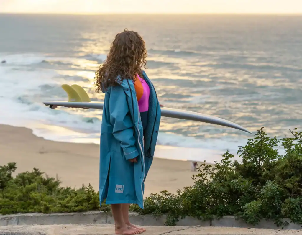 Planche de surf opti avec femme au bord de la mer en sunset, sports de paddle, surf et ocean.