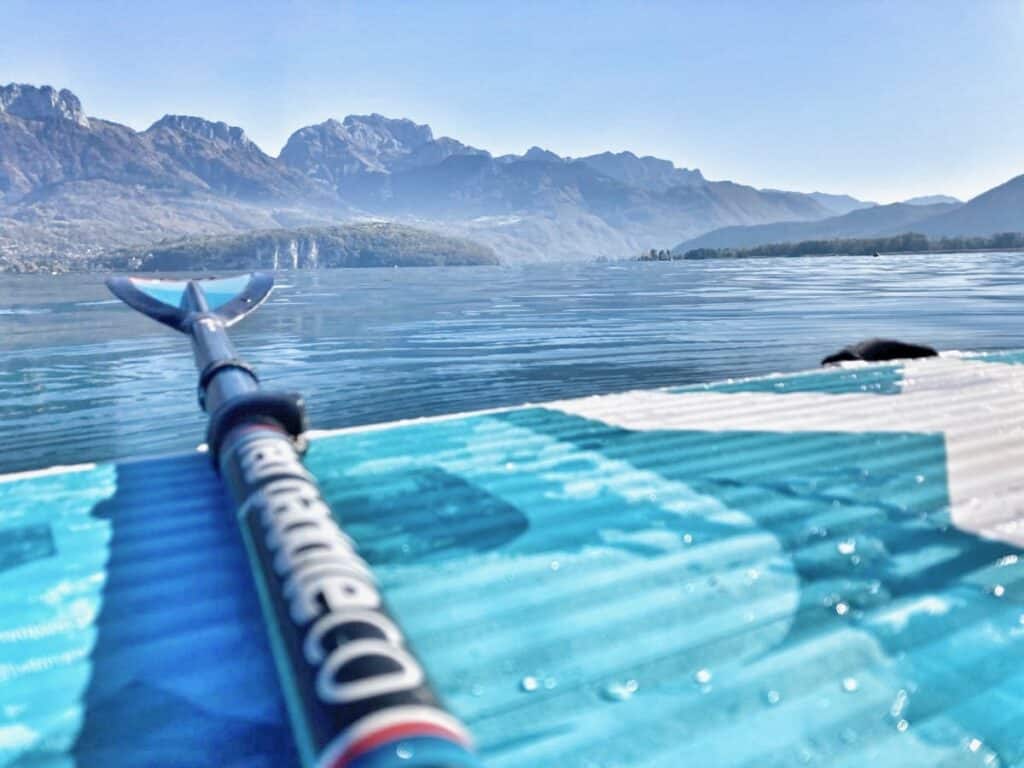 Sticks de stand-up paddle sur l'eau avec montagnes en arrière-plan, idéal pour la pratique du SUP en nature.