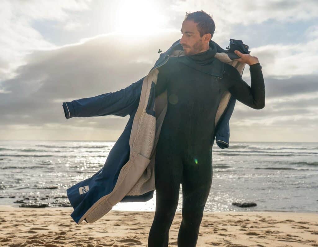 Vêtements de surf et paddle opti, homme prêt pour sport aquatique à la plage.