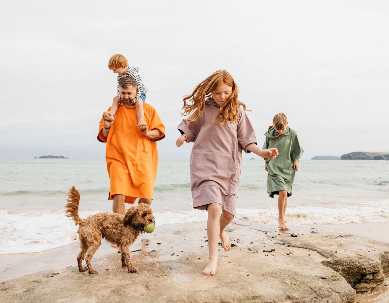 Famille sur la plage prête pour une journée au bord de l'eau, paddle et matériel